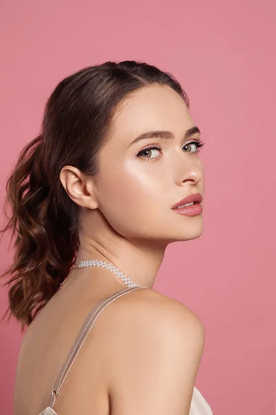 ピンクの背景にエレガントな真珠のネックレスを身に着けている若い女性 — ストック写真