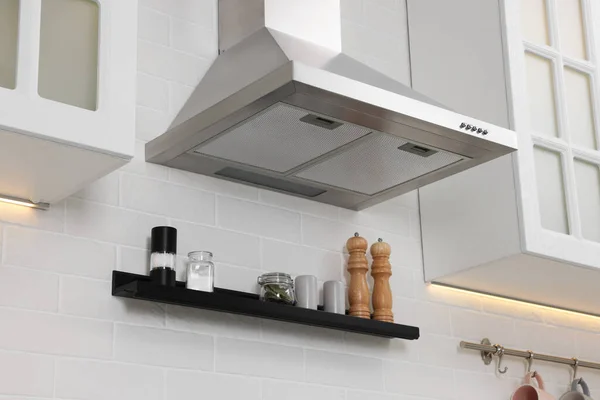 Modern range hood over shelf with spices in kitchen