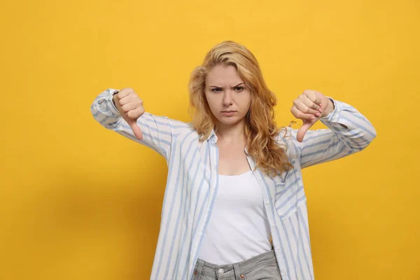 Незадоволена Молода Жінка Показує Великі Пальці Вниз Жовтому Тлі — стокове фото