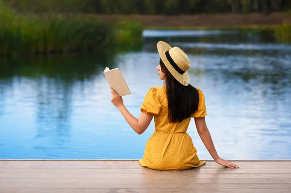 女人在湖边的码头看书 后视镜 — 图库照片