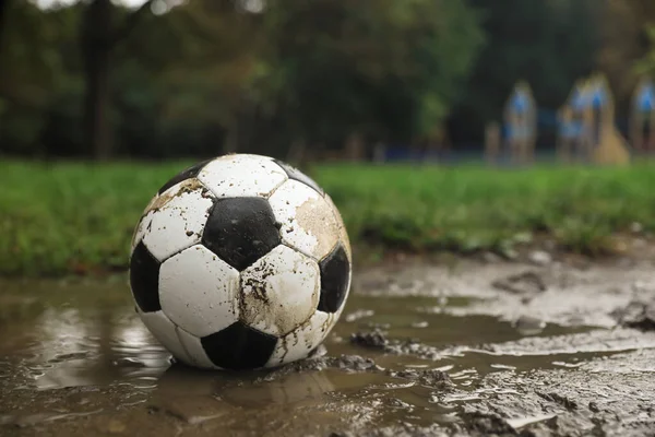 stock image Dirty leather soccer ball in puddle outdoors