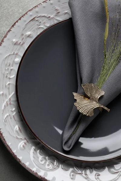 Fabric napkin and decorative ring for table setting on gray plate, top view