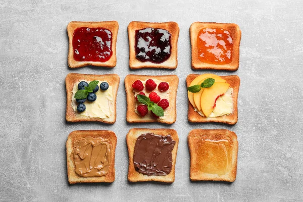 stock image Tasty toasts with different spreads and fruits on light grey table, flat lay