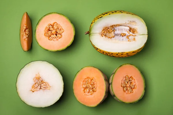 Cut different types of melons on green background, flat lay