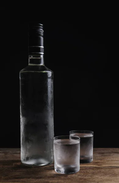 ブラックを背景に木製のテーブルの上にウォッカとショットグラスのボトル テキストのスペース — ストック写真