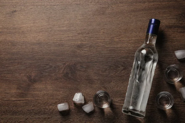 ウォッカのボトル 木製のテーブルにショットグラスと氷のキューブ フラットレイアウト テキストのスペース — ストック写真