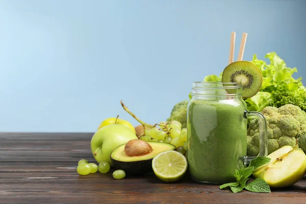 stock image Green smoothie in mason jar and fresh ingredients on wooden table. Space for text