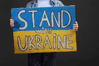Çocuk elinde poster tutarken Ukrayna ile birlikte gri arka planda, yakın plan