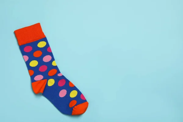 New sock with pattern on light blue background, top view. Space for text