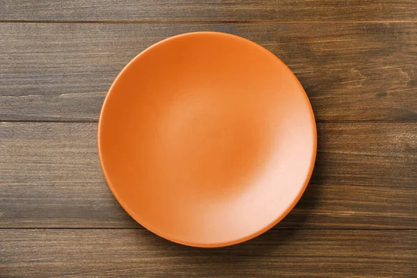 Pusty Pomarańczowy Ceramiczny Talerz Drewnianym Stole Widok Góry — Zdjęcie stockowe