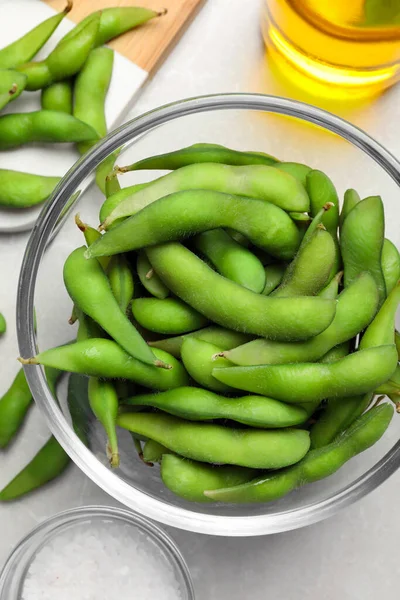 Green edamame beans in pods served on light grey table, flat lay