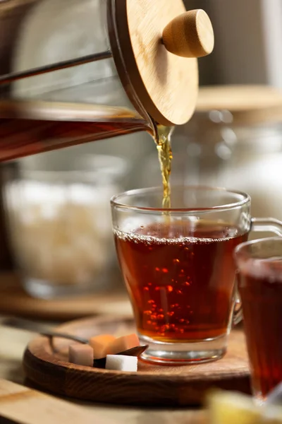 stock image Pouring delicious tea into glass cup on table, closeup