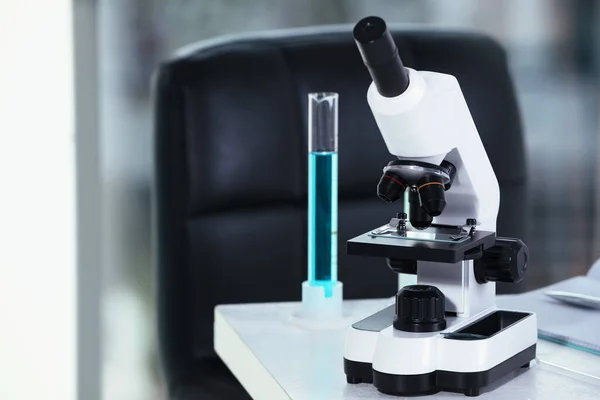 Modern microscope with glass slide on white table in laboratory, space for text