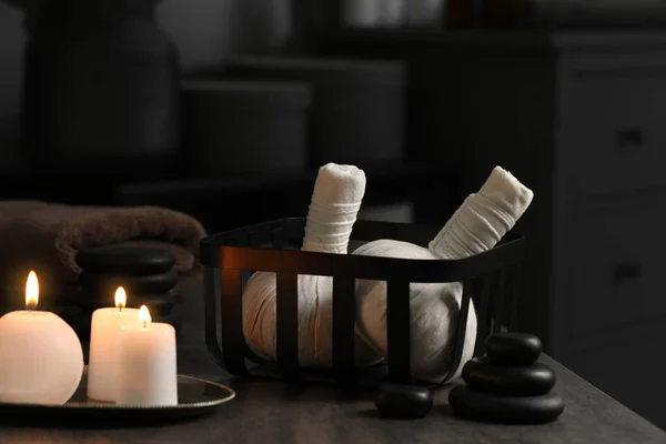 草药按摩袋 燃烧蜡烛和石头在灰色的桌子上 温泉产品 — 图库照片