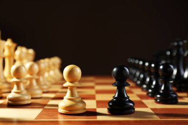 Koyu arkaplana karşı tahta üzerinde satranç taşları. Rekabet konsepti