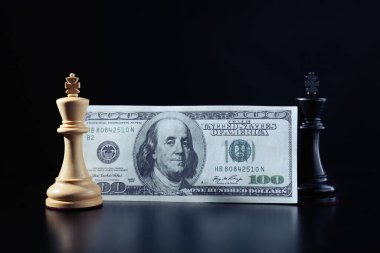 Para, beyaz ve siyah papazlar karanlık arka plana karşı. İş yarışması konsepti