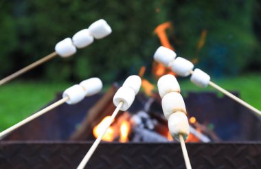 Delicious puffy marshmallows roasting over bonfire, closeup clipart