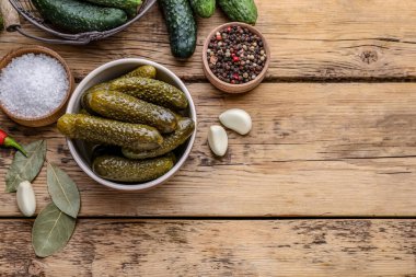 Bir kase salatalık turşusu ve ahşap masa üzerindeki malzemeler. Metin için boşluk