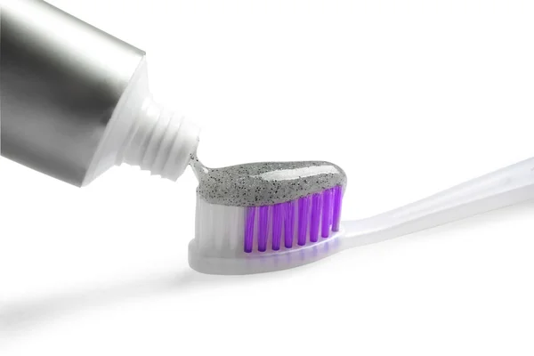 Tube of charcoal toothpaste and brush on white background