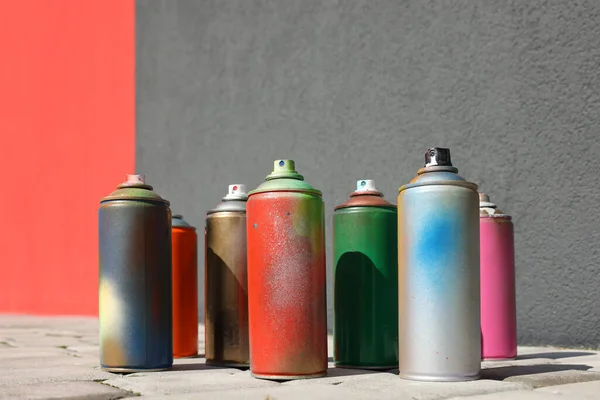 Cans Different Spray Paints Pavement Wall — Stock Photo, Image