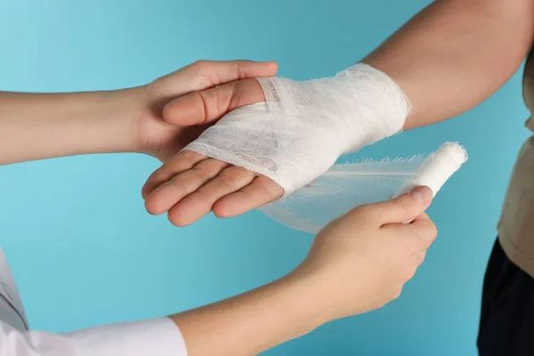 Médico Aplicando Bandagem Mão Paciente Fundo Azul Claro Close — Fotografia de Stock