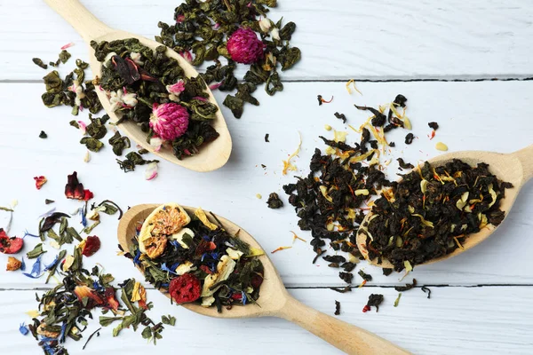 Stock image Flat composition with spoons of dried herbal tea leaves on white wooden table