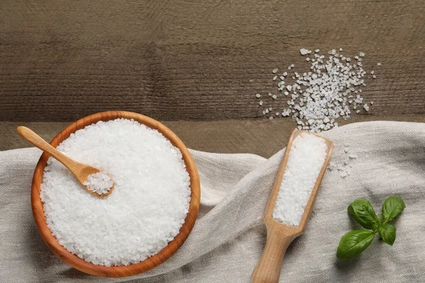 stock image Natural sea salt and basil leaf on wooden table, flat lay. Space for text