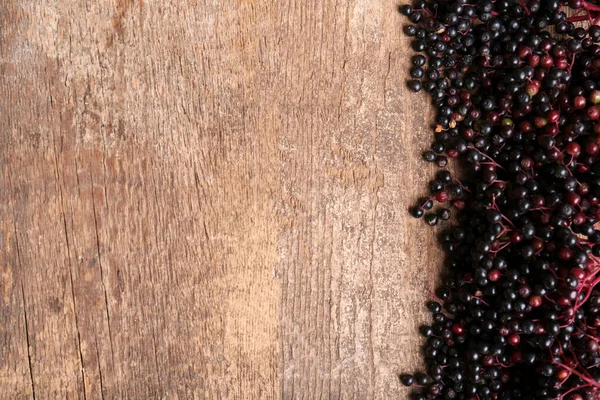 stock image Tasty elderberries (Sambucus) on wooden table, top view. Space for text