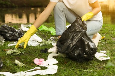 Plastik çantalı kadın parkta çöp topluyor, yakın plan.