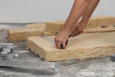 Kapalı alanda yalıtım malzemelerini ölçen ve kesen işçiler.