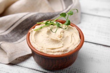 Beyaz ahşap masada nefis humus ile kase, yakın plan.