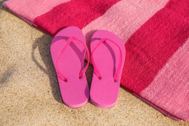 Plaj havlusu ve kumda şık terlikler.