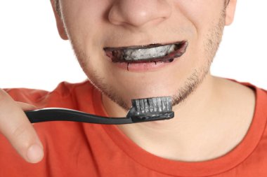 Man brushing teeth with charcoal toothpaste on white background, closeup