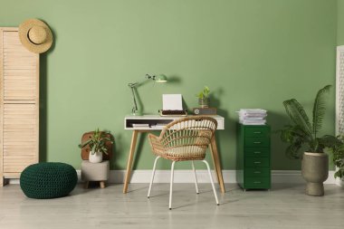 Writer's workplace with typewriter on wooden desk near pale green wall in room