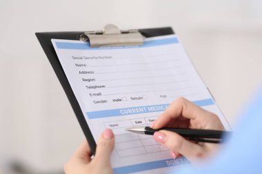 Klinikte hastanın sağlık kartını dolduran doktor, yakın plan.