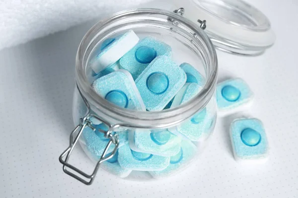 Jar with water softener tablets on white table, closeup