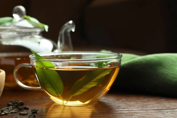 茶杯中的新鲜绿茶 木桌上有叶子 — 图库照片