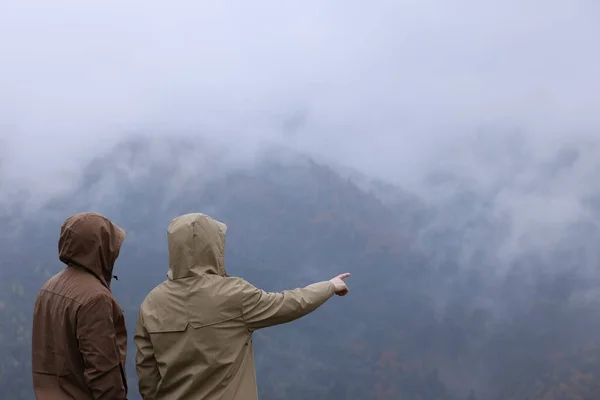山の景色を楽しむレインコートの男と女 — ストック写真