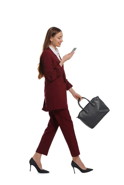 Jovem Mulher Terno Borgonha Usando Smartphone Enquanto Caminha Sobre Fundo — Fotografia de Stock