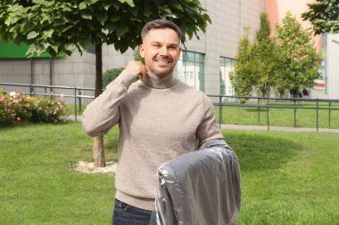 Elbiseleri açık havada tutan bir adam. Kuru temizleme servisi.