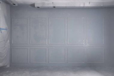 Odasında çerçeveler olan gri, yeni boyanmış bir duvar.