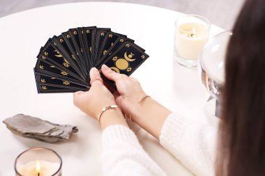 Soothsayer with tarot card at table, closeup clipart