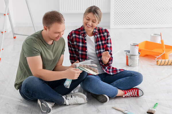 Счастливая пара с обломками краски обсуждают новый цвет стен в квартире во время ремонта