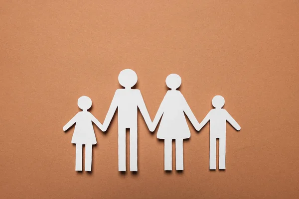 Paper family figures on brown background, top view. Insurance concept