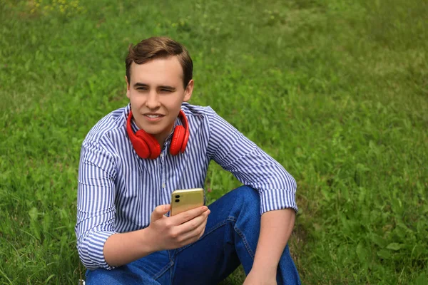 Schöner Junger Mann Mit Kopfhörer Und Smartphone Grünen Gras — Stockfoto