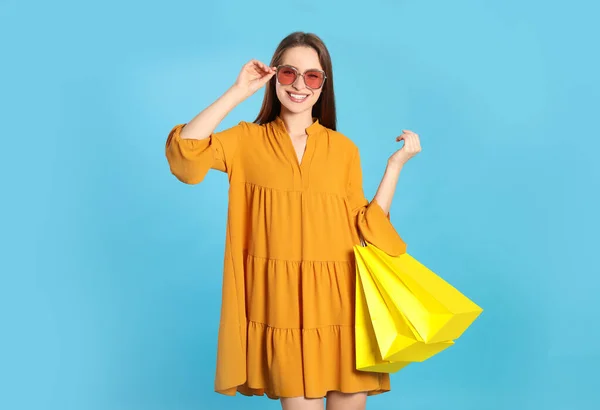 明るい青の背景にショッピングバッグと幸せな若い女性 大販売 — ストック写真
