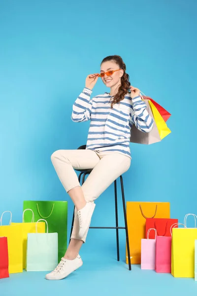 快乐的女人 戴着时髦的太阳镜 提着五颜六色的购物袋 脚背浅蓝色 — 图库照片