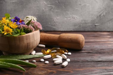 Taze otlu havan, çiçekler ve haplar ahşap masada, mesaj için yer