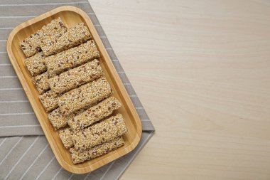 Ahşap masa üzerinde lezzetli susam tohumu çubukları olan bir tabak, üst manzara. Metin için boşluk