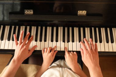 Piyano çalan çocuklu genç bir kadın. Müzik dersi